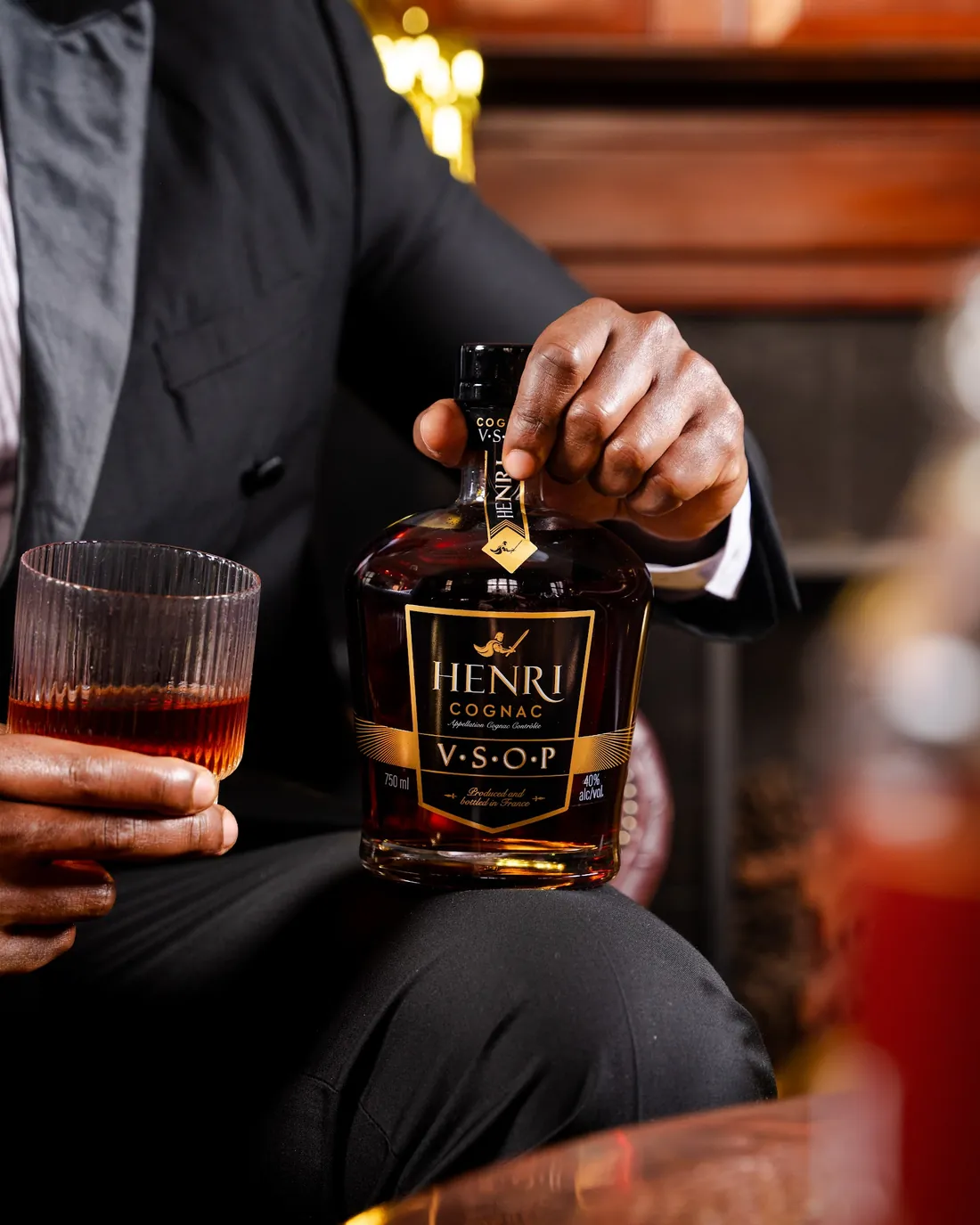 Hands pouring Henri V.S.O.P beside a cut-crystal glass
